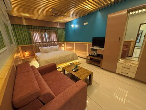 Une chambre d’hôtel comprenant un lit, un canapé, une télévision, une armoire et un miroir.