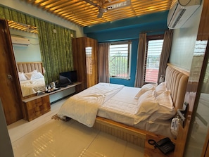 Une chambre d’hôtel avec un lit, une télévision, un bureau et une fenêtre avec des rideaux.