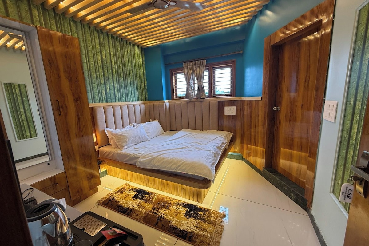 Une chambre à coucher avec un lit, une fenêtre avec des rideaux, un ventilateur de plafond et des murs en bois.