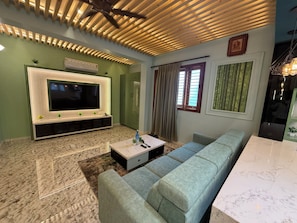 Un salon équipé d’un t éléviseur à écran plat, d’un canapé, d’une table basse et d’un ventilateur de plafond.