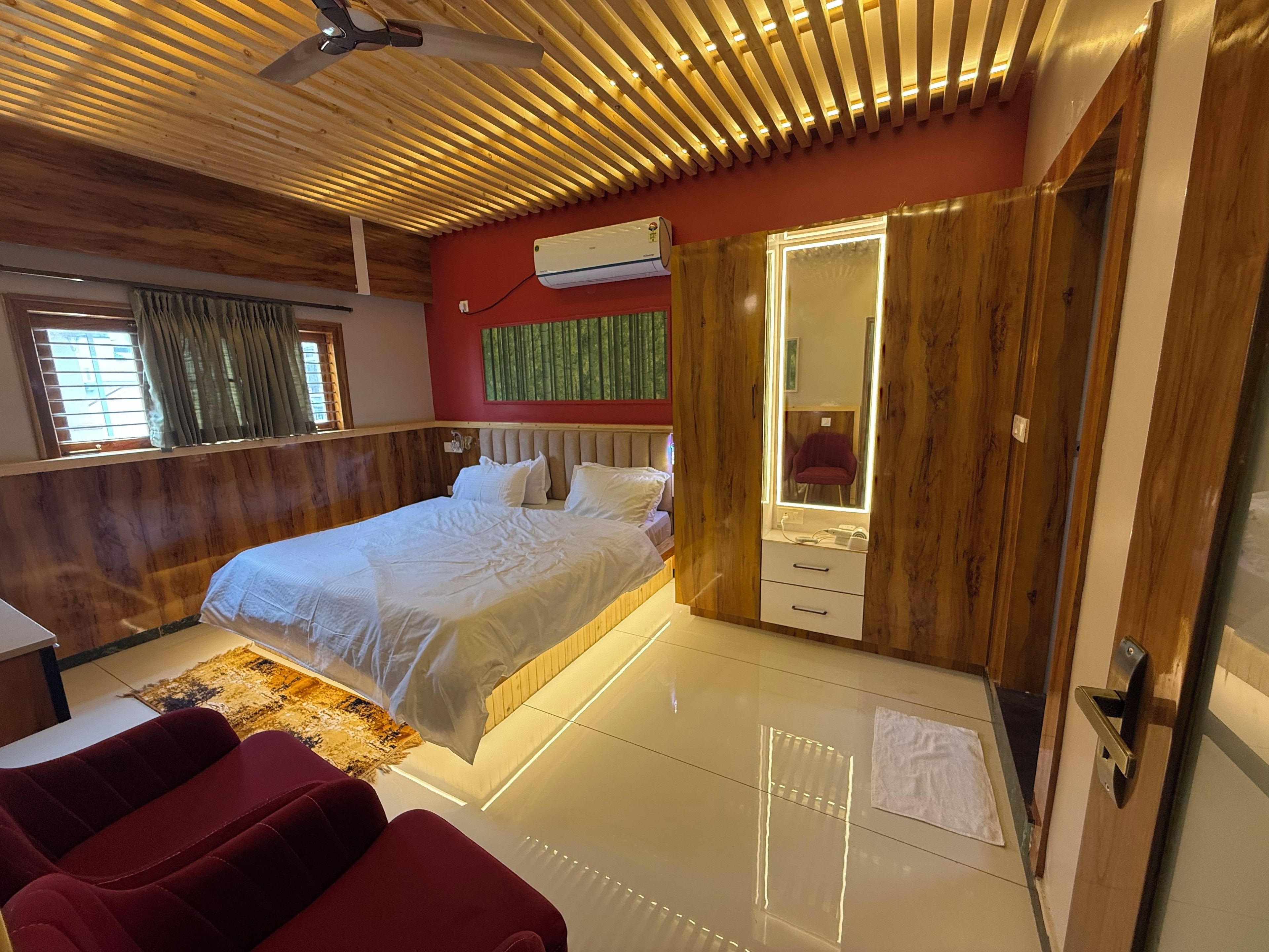 Ein Schlafzimmer mit einem Bett, einem Frisiertisch mit Spiegel, einer roten Wand und einem Deckenventilator.