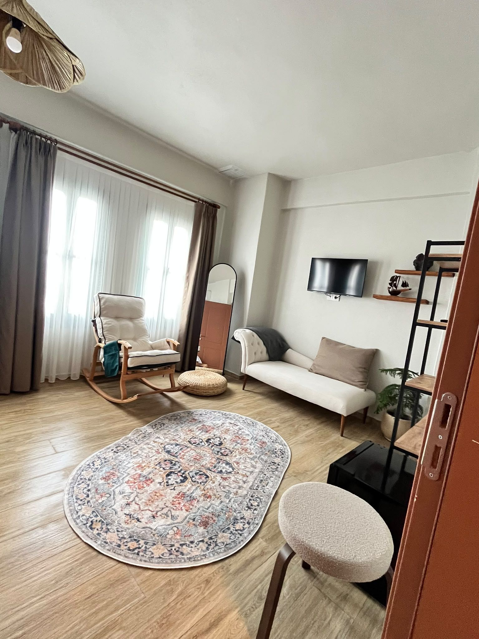 A living room with a sofa, a chair, a television, a rug, and a wooden floor.