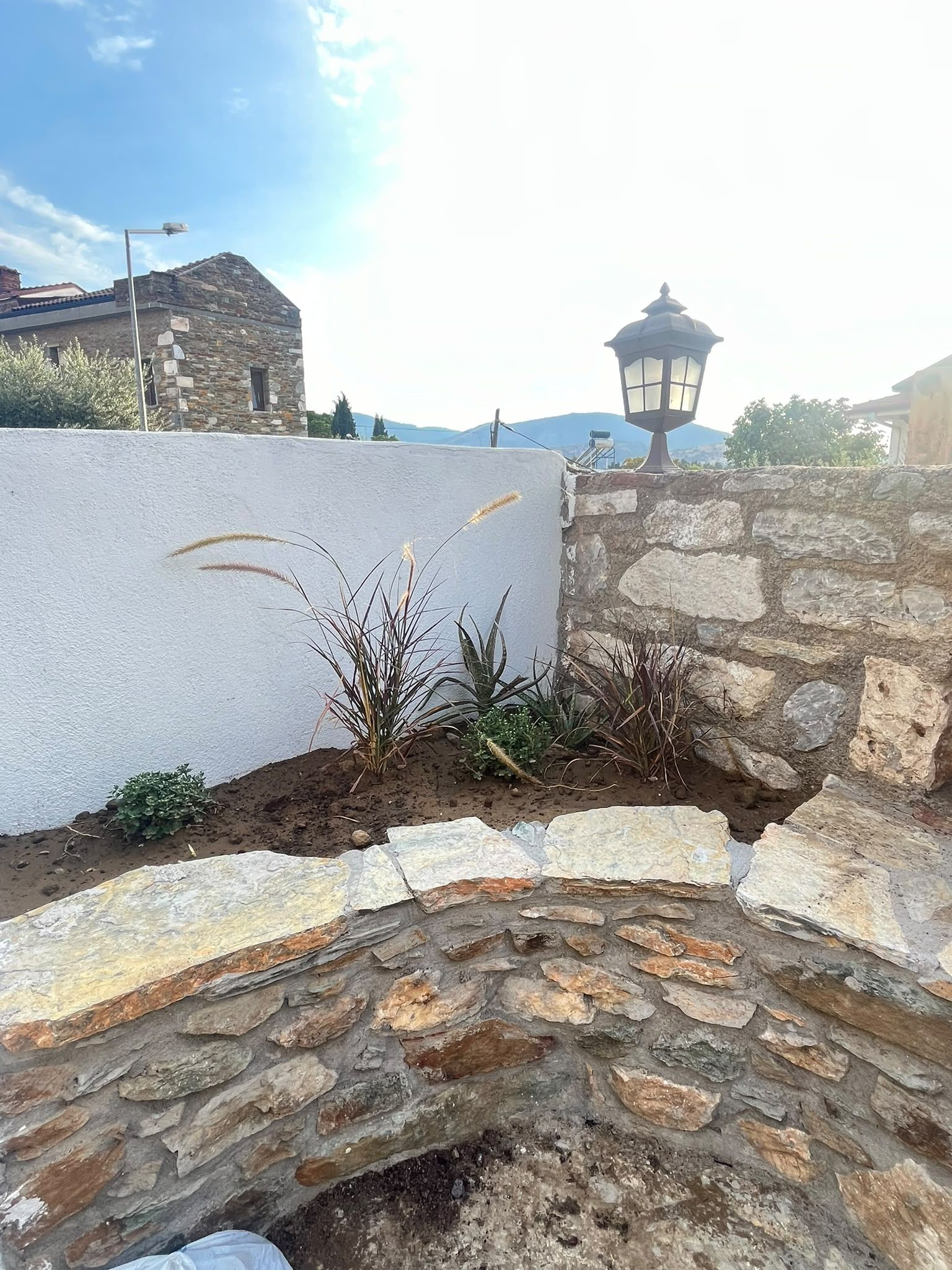 A stone wall with a white wall and a lamp post.