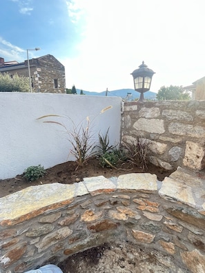 A stone wall with a white wall and a lamp post. - Marsel Rooms (İzmir)
