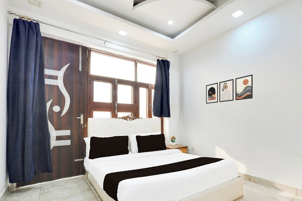 Une chambre à coucher avec un lit, des rideaux, une fenêtre et des œuvres d’art murales.