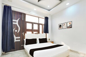 Une chambre à coucher avec un lit, des rideaux, une fenêtre et des œuvres d’art murales.