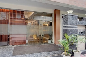A hotel entrance with a glass door, a marble pillar with the number 257, and potted plants. - Hotel O Urban Sky (Gurugram)