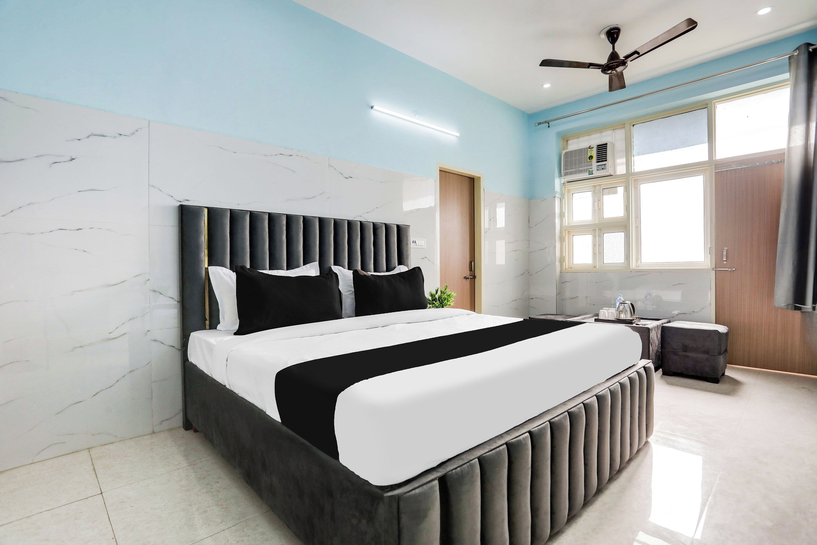 Una camera da letto moderna con un letto, una ventola a soffitto, una finestra e un tavolino con una pianta.