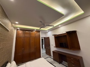 A bedroom with a wardrobe, a bed, a desk, and a television. - Road B (New Delhi)