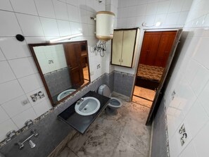 A bathroom with two toilets, a sink, a mirror, and a cabinet. - Road B (New Delhi)
