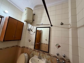 A bathroom with a toilet, sink, mirror, and a towel rack. - Road B (New Delhi)