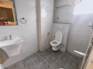 A bathroom with a white sink, toilet, and a shower area. - RITHANYA SUITES (Bengaluru)
