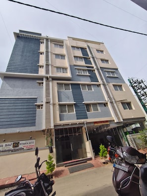 A multi-story building with a sign for 'RITHANYA SUITES' indicating available deluxe rooms. - RITHANYA SUITES (Bengaluru)
