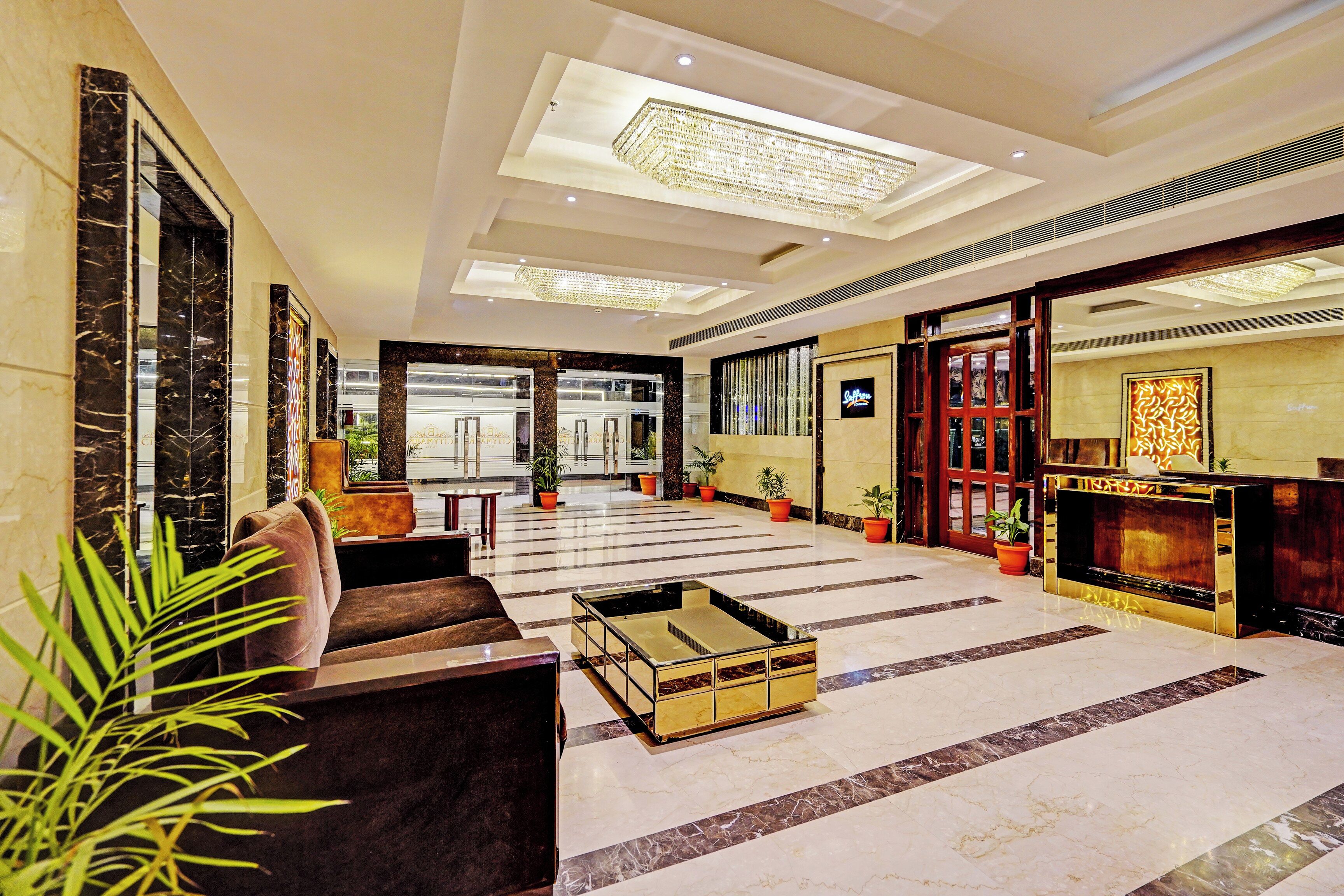 A hotel lobby with a marble floor, a reception desk, and a seating area with a sofa and a coffee table.