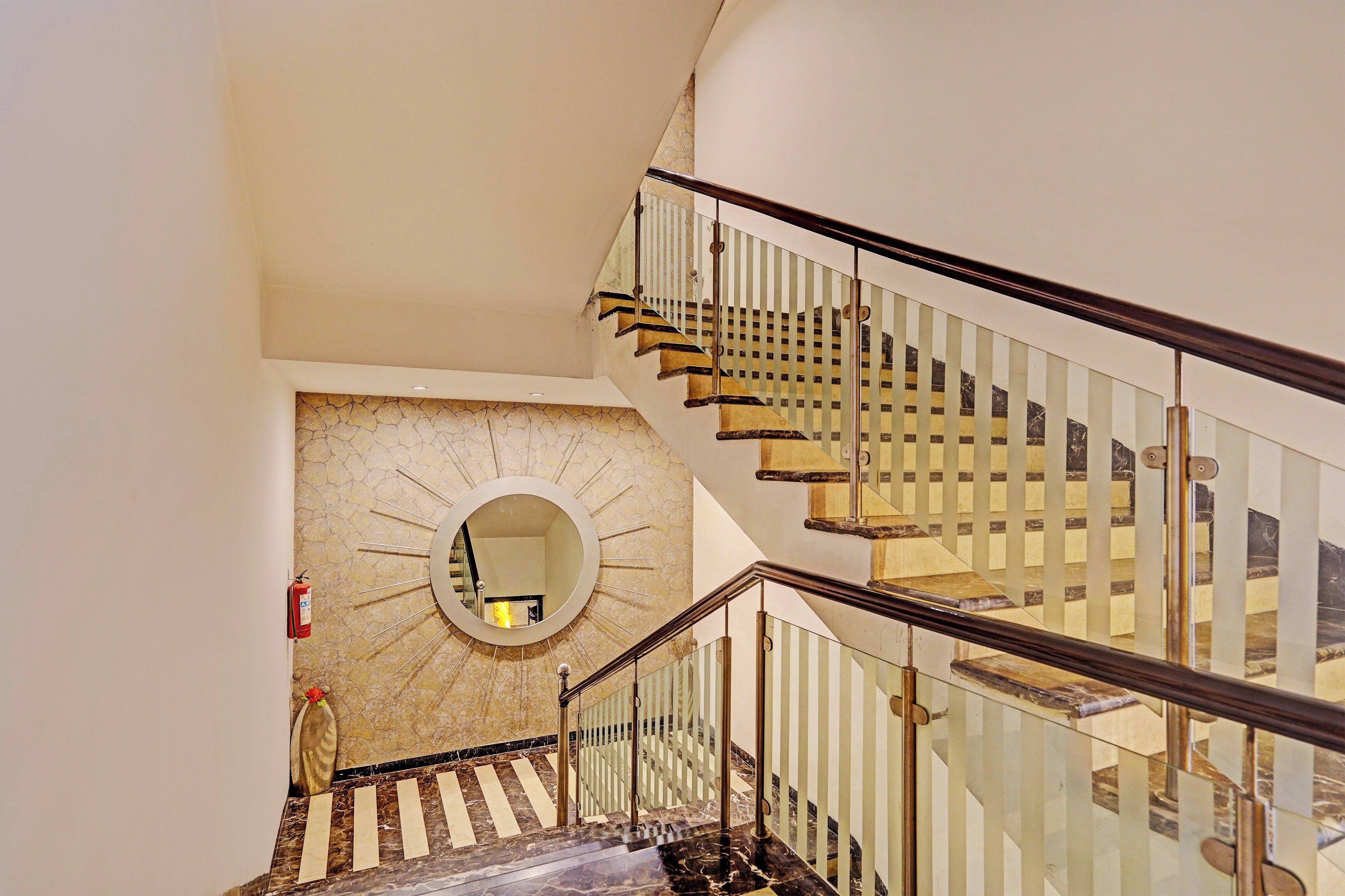 A staircase with glass railings and a circular mirror on the wall.