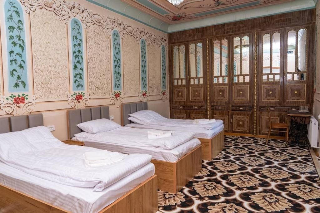 Una camera d'albergo con tre letti, un armadio in legno e un pavimento decorato.