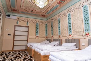 Ein Hotelzimmer mit vier Betten, einem Chandelier und aufwendigen Wandverzierungen.