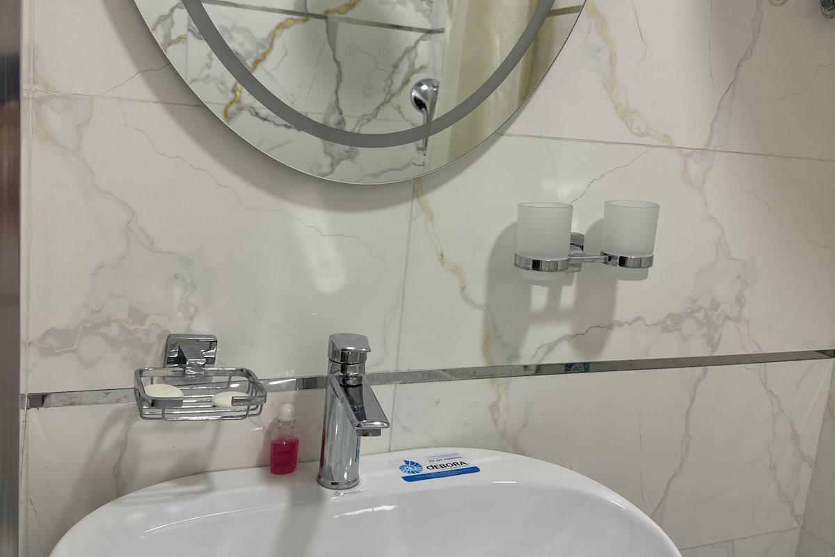 Ein Badezimmer mit einem weißen Waschbecken, einem Spiegel und einer Duschbrause.