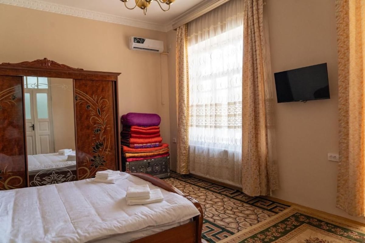 Ein Hotelzimmer mit Bett, Kleiderschrank, Fernseher und einem Fenster mit Vorhängen.