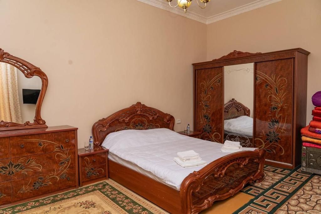 A bedroom with a wooden bed, a dresser, a wardrobe, and a mirror.