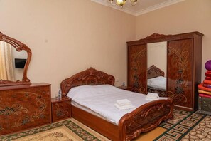 Quarto com cama de madeira, penteadeira, guarda-roupa e espelho.