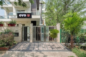 Entrada d'un hotel amb una entrada tancada per reixes, plantes en testos i un cartell que diu 'OYO Hotel Royal Inn'.