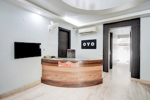 Een modern ontworpen receptiebalie, een wandgemonteerde televisie en een airconditioner aan de muur.