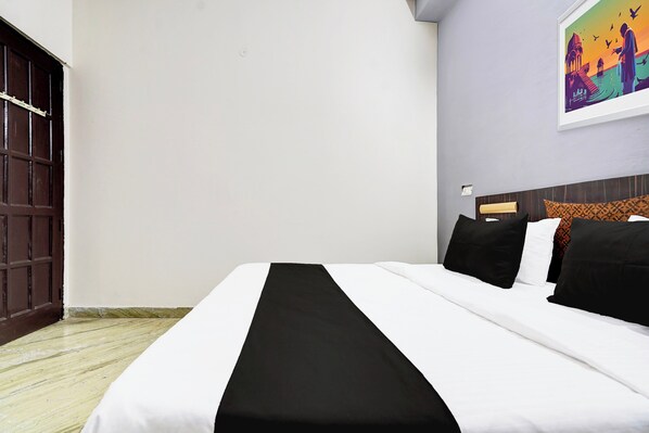 Una habitación de hotel con una cama, una puerta de madera y un cuadro en la pared.