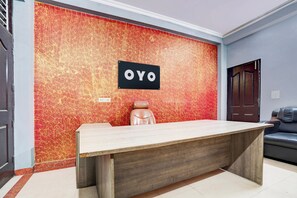En reception med et 'OYO' skilt, en læderstol og en mørk dør.