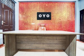 Una recepción con mostrador de madera y pared texturizada de color rojo con un cartel que dice 'OYO'.