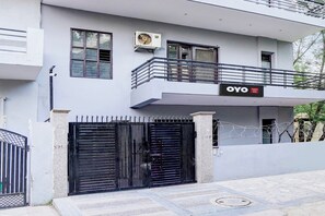 Un edificio de dos pisos con un balcón, un letrero que dice 'OYO Shubham Guest House' y una entrada con portón.