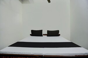 Ein schlichter Raum mit einem Bett, zwei Kissen und einer schlichten weißen Wand.