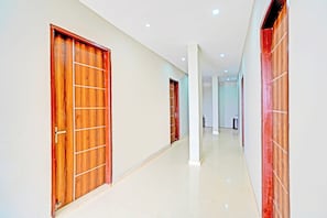 Un pasillo con puertas de madera y paredes blancas.