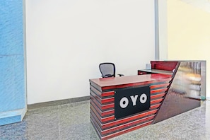 En receptionsdisk med et skilt, der viser 'OYO', og en stol foran.