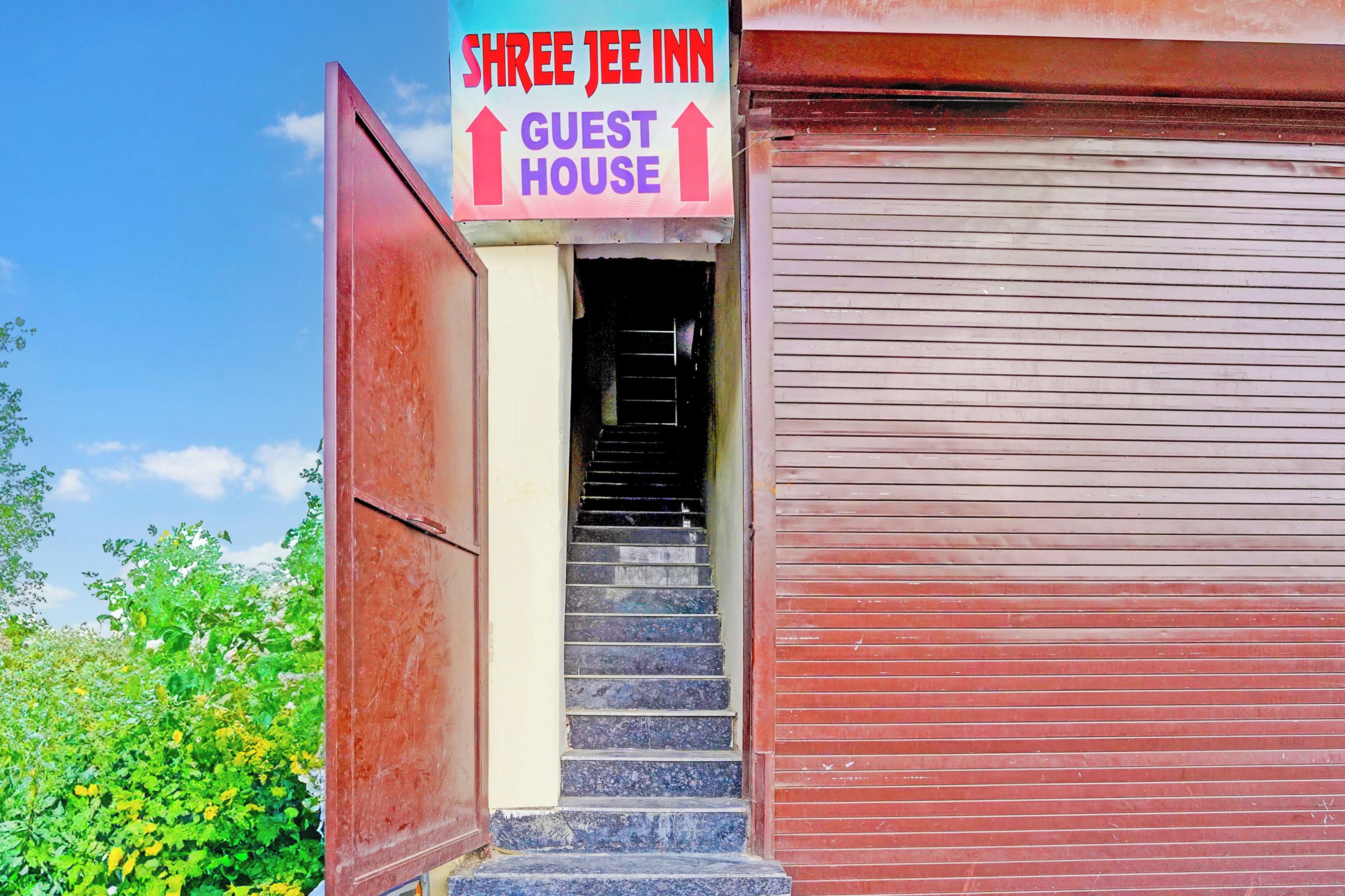 A hotel entrance with a sign for the 'Shree Jey Inn Guest House' and a staircase leading inside.