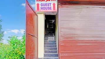 A hotel entrance with a sign for the 'Shree Jey Inn Guest House' and a staircase leading inside.