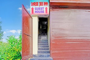 Entrada de un hotel con un letrero que dice 'Shree Jey Inn Guest House' y una escalera que conduce al interior.