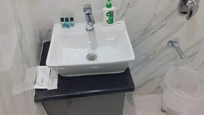 A bathroom sink with a mirror, a faucet, and toiletries on the countertop. - Hotel Shyamagiri (Ranopali)