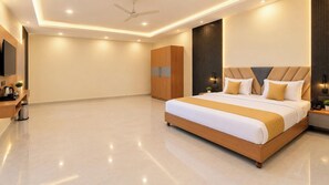A modern bedroom with a large bed, a wardrobe, a desk, and a ceiling fan. - Hotel Shyamagiri (Ranopali)