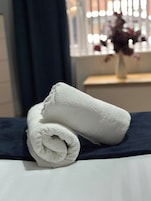 Una toalla blanca doblada con cuidado sobre una cama con cubrecama azul oscuro.