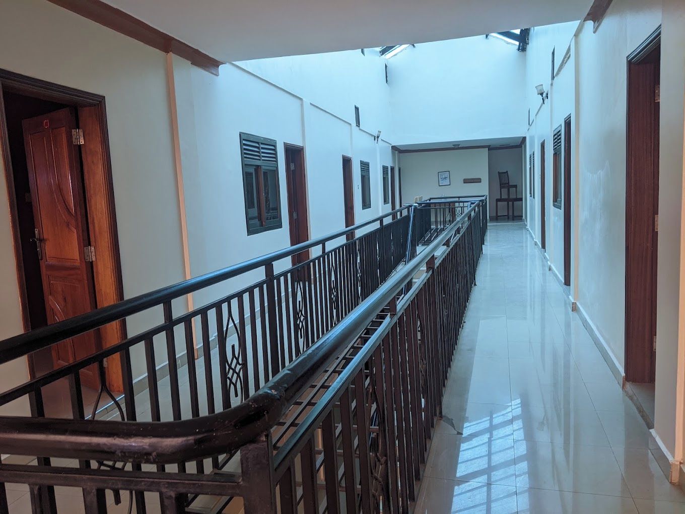 A corridor with a wooden railing, doors, and windows.