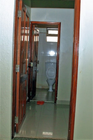 Un corridoio stretto che conduce a un bagno con il water e un paio di pantofole rosse sul pavimento.
