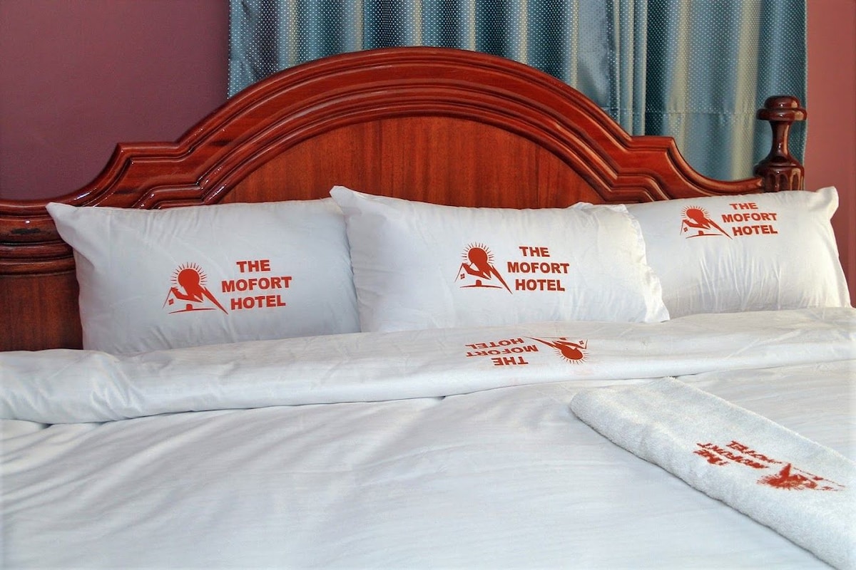 Un letto d'hotel con biancheria e cuscini che presentano il logo dell'hotel.