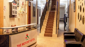 Un'area reception di un hotel, con una scrivania, una scala e una zona salotto.