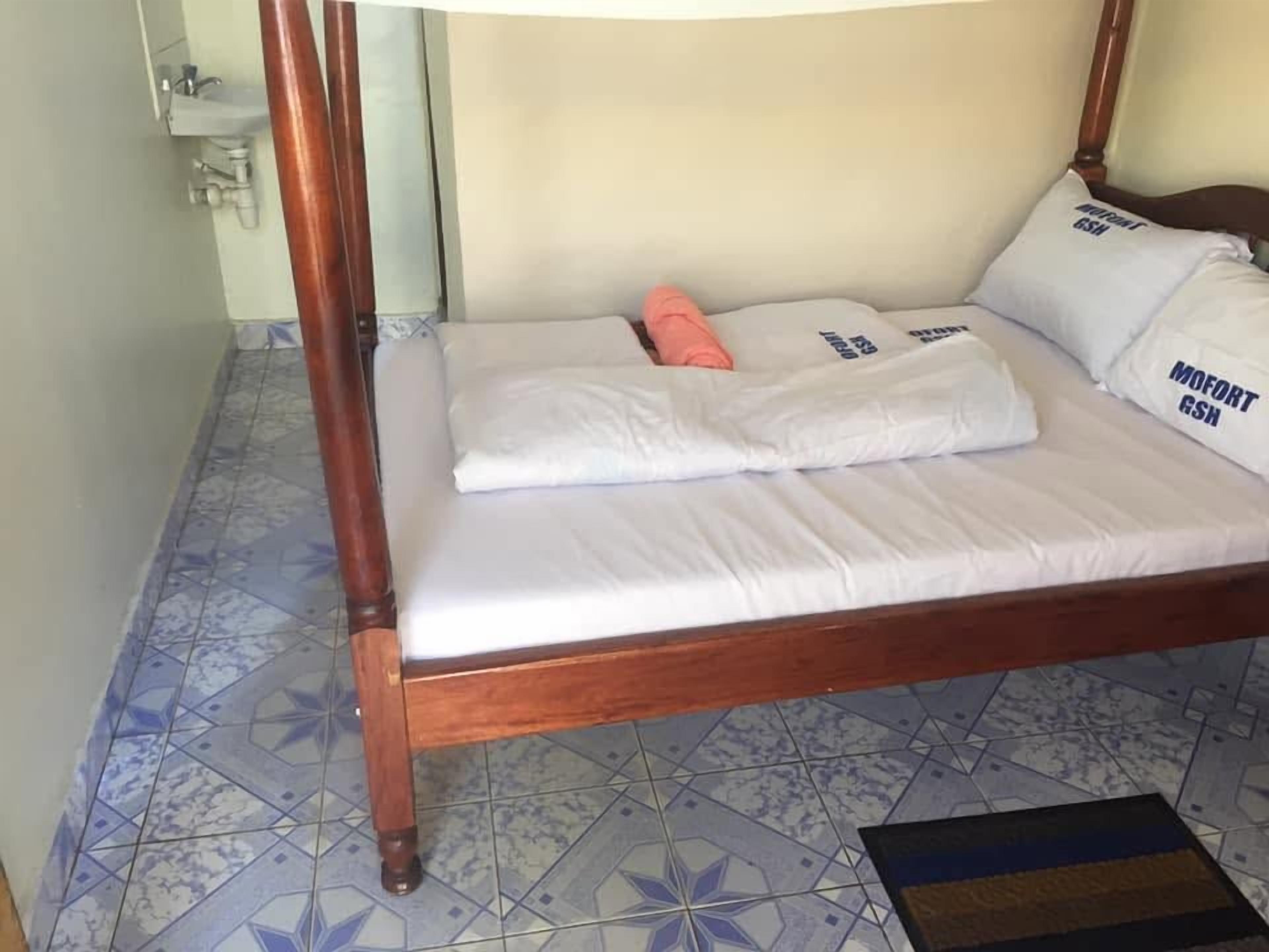 A single bed with a wooden frame, white bedding, and pillows with text.