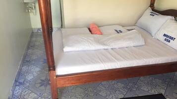 A single bed with a wooden frame, white bedding, and pillows with text.