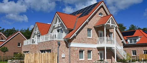 En bostadsbyggnad med en fasad av tegel, röda takpannor och en balkong.