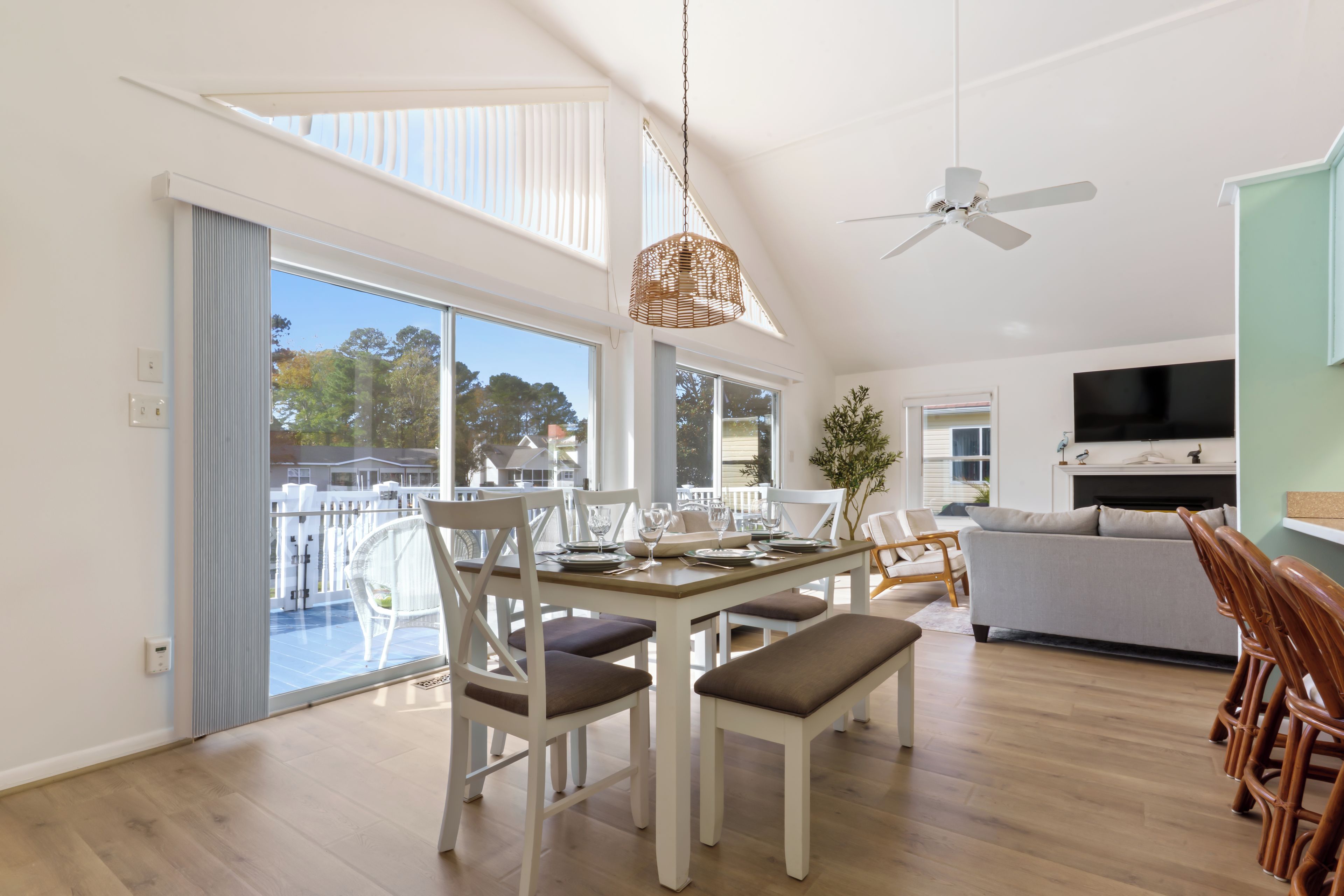 A modern living room with a dining area, a ceiling fan, and a TV.