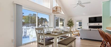 A modern living room with a dining area, a ceiling fan, and a TV.