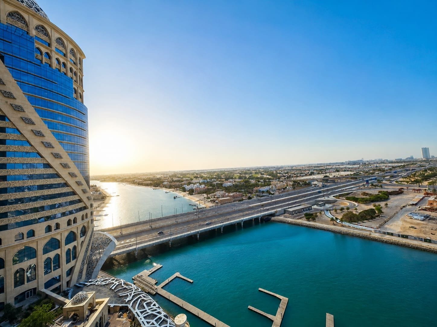 Un hôtel situé au bord de l’eau, doté d’un design moderne, caractérisé par une grande façade en verre et une structure incurvée originale.